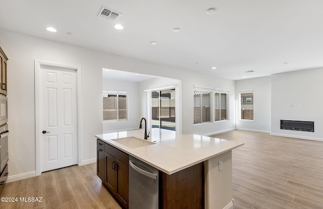 kitchen featuring a kitchen island with sink, sink, light hardwood / wood-style flooring, appliances with stainless steel finishes, and dark brown cabinets