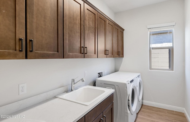 washroom featuring light hardwood / wood-style floors, cabinets, sink, and washing machine and dryer