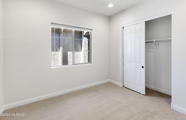 unfurnished bedroom featuring a closet and light colored carpet