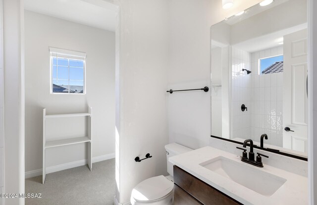 bathroom featuring toilet, vanity, and tiled shower