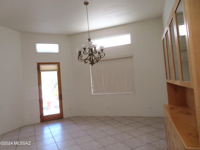 unfurnished dining area with a notable chandelier, a high ceiling, and light tile patterned floors