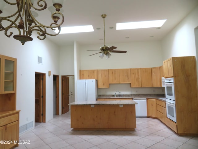 kitchen featuring a towering ceiling, white appliances, ceiling fan, light tile patterned floors, and a kitchen island