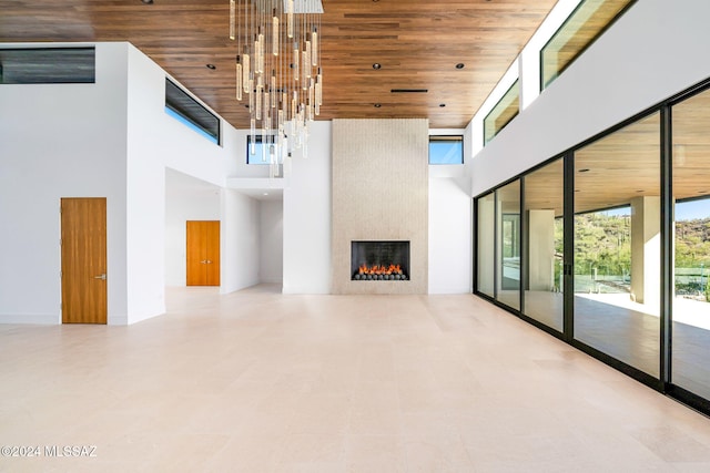 unfurnished living room with wooden ceiling, a high ceiling, and a fireplace