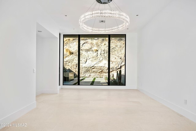 spare room featuring expansive windows and an inviting chandelier