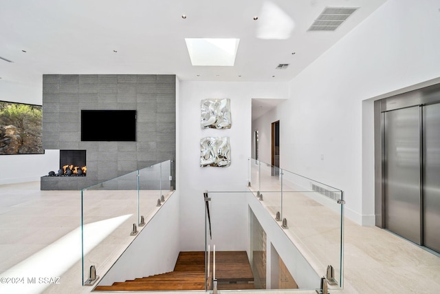 interior space featuring elevator, a tiled fireplace, and a skylight