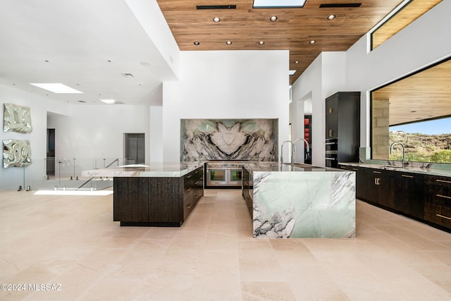 kitchen featuring dark brown cabinets, a high ceiling, a skylight, wooden ceiling, and a spacious island