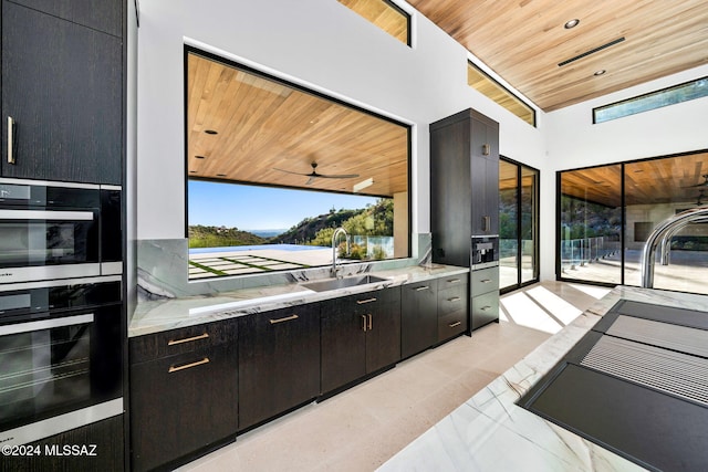 kitchen with multiple ovens, sink, ceiling fan, and wood ceiling