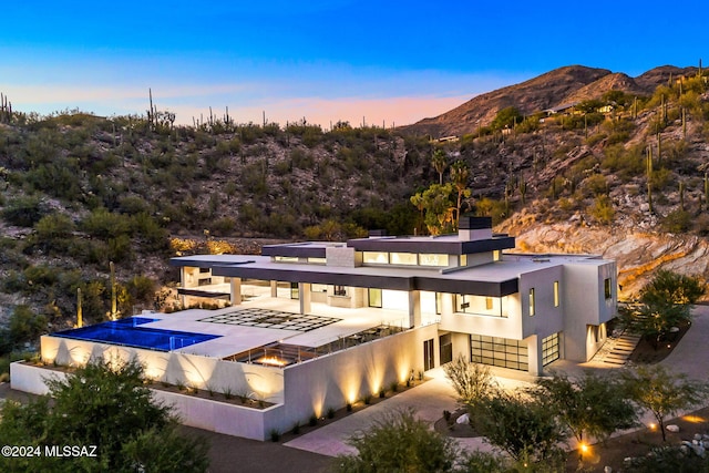 3569 E Secret Canyon Pl, Tucson, AZ 85718 - rear view of house with a mountain view, stucco siding, an infinity pool, and a chimney