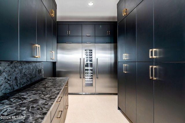 kitchen with dark stone counters, tasteful backsplash, and high end fridge