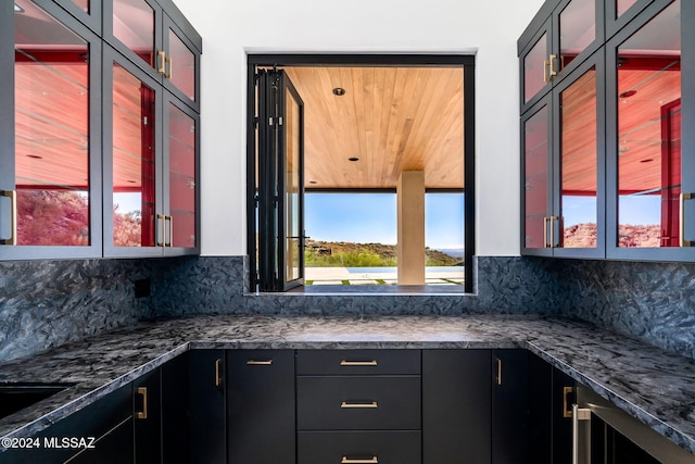 kitchen with plenty of natural light, dark stone counters, and tasteful backsplash