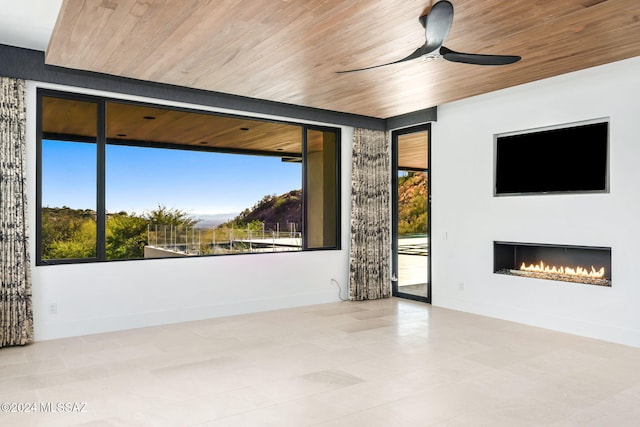 empty room featuring a wealth of natural light, ceiling fan, and wood ceiling