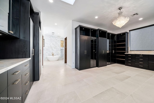 interior space with connected bathroom, an inviting chandelier, and light tile patterned floors