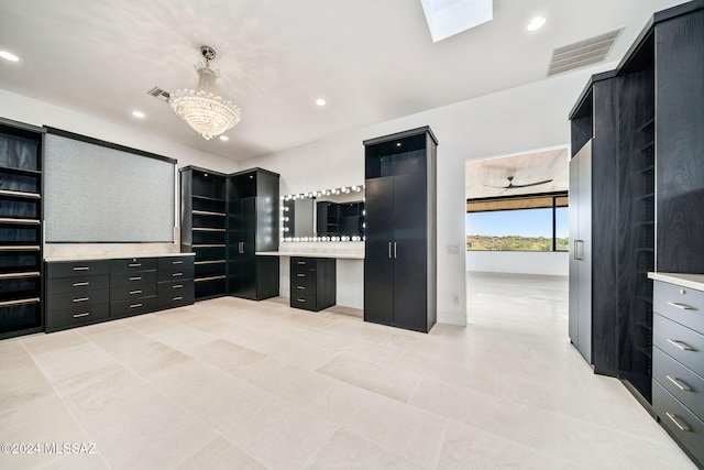 spacious closet with light tile patterned floors, a skylight, and a notable chandelier