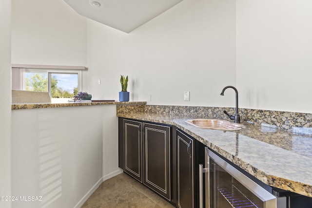 interior space featuring sink, wine cooler, light stone countertops, dark brown cabinets, and light tile patterned flooring