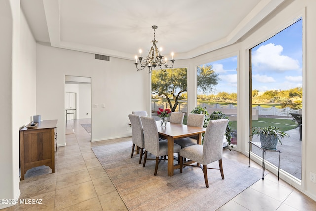 dining space featuring a tray ceiling, light tile patterned flooring, and an inviting chandelier