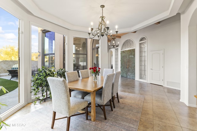 dining area with light tile patterned floors, a wealth of natural light, and an inviting chandelier