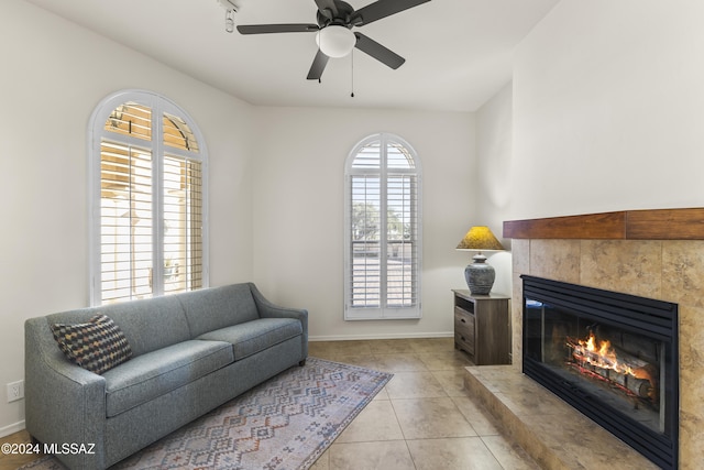 tiled living room with a tile fireplace and ceiling fan