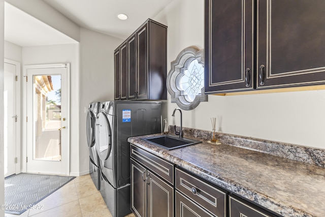 laundry area featuring cabinets, light tile patterned floors, washer and clothes dryer, and sink