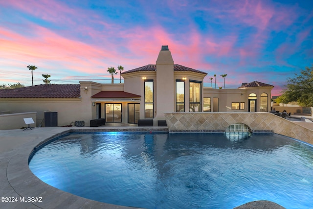 pool at dusk with a patio area