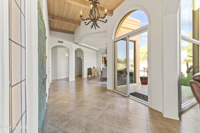 interior space featuring beamed ceiling, a towering ceiling, an inviting chandelier, and wooden ceiling