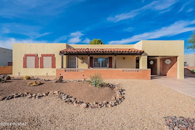 pueblo-style home featuring stucco siding and a tiled roof