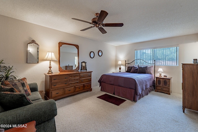 bedroom featuring light carpet, ceiling fan, and a textured ceiling