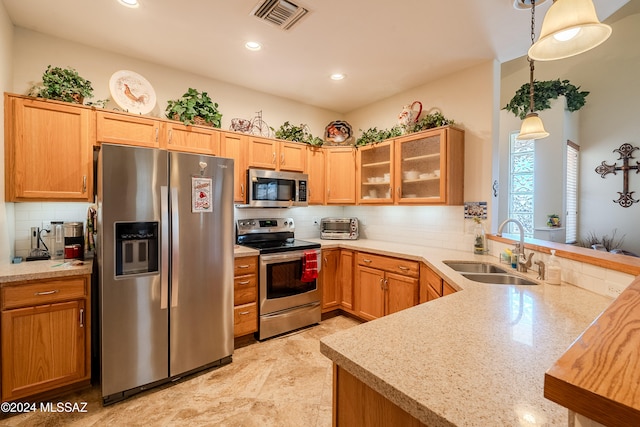 kitchen with stainless steel appliances, sink, kitchen peninsula, decorative light fixtures, and decorative backsplash