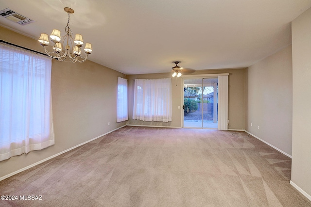 empty room with light colored carpet and ceiling fan with notable chandelier