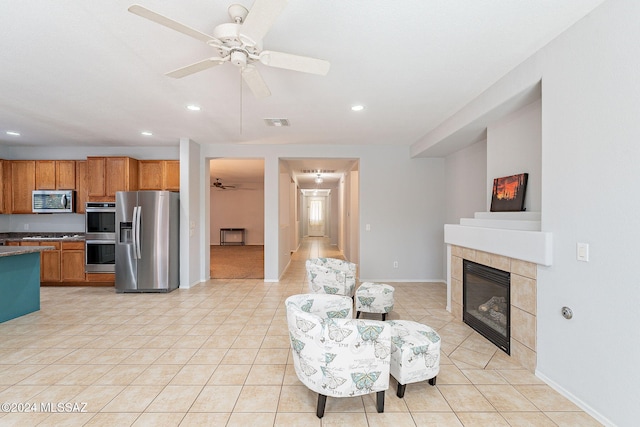 kitchen featuring light tile patterned floors, stainless steel appliances, visible vents, a ceiling fan, and a tile fireplace