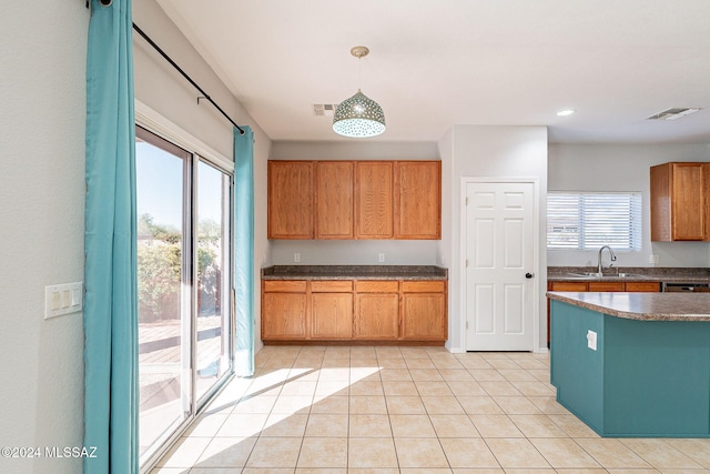 kitchen with light tile patterned floors, a sink, visible vents, a wealth of natural light, and dark countertops