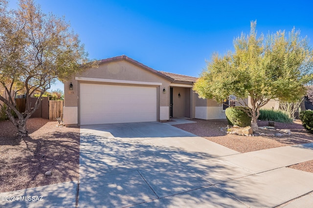 single story home featuring a tile roof, stucco siding, fence, a garage, and driveway