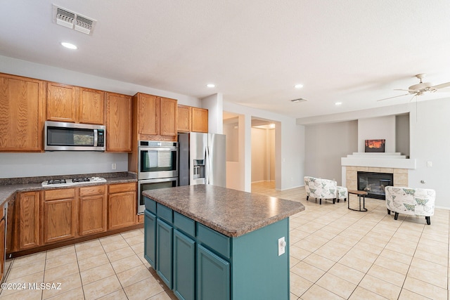 kitchen with light tile patterned floors, visible vents, a tile fireplace, dark countertops, and appliances with stainless steel finishes