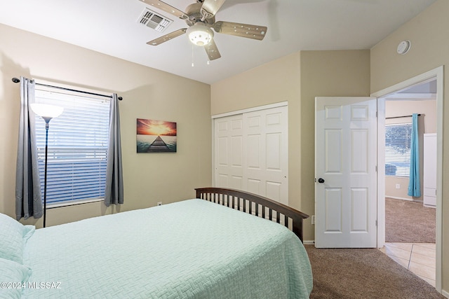 carpeted bedroom with ceiling fan, visible vents, a closet, and tile patterned floors