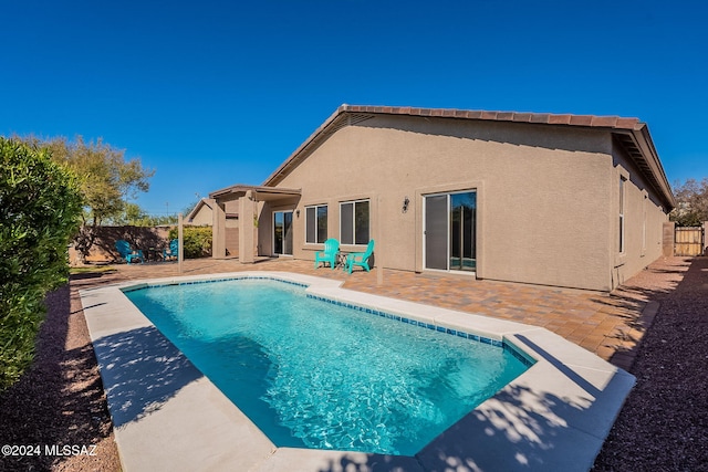 back of property with stucco siding, a fenced backyard, a fenced in pool, and a patio