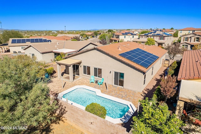 back of property featuring a residential view, roof mounted solar panels, a patio, and stucco siding