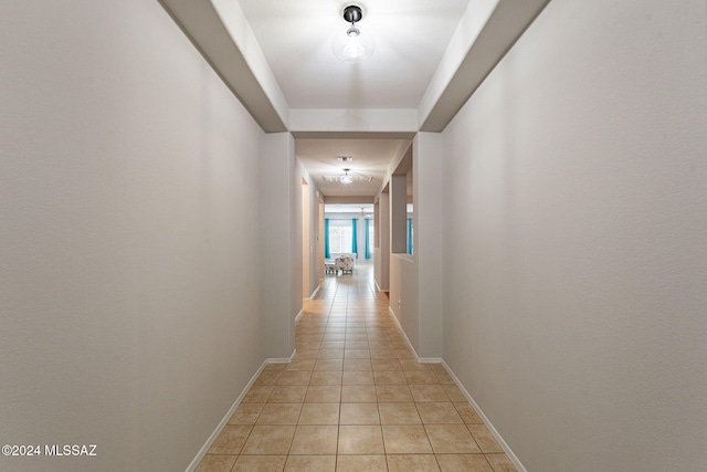 hallway with light tile patterned floors and baseboards