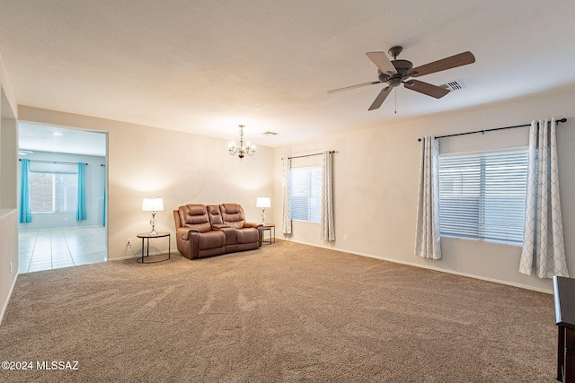 sitting room featuring carpet, ceiling fan with notable chandelier, visible vents, baseboards, and tile patterned floors