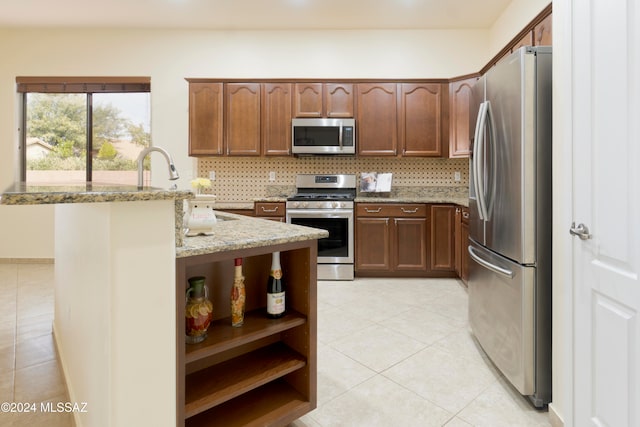 kitchen featuring light stone countertops, appliances with stainless steel finishes, backsplash, sink, and light tile patterned floors