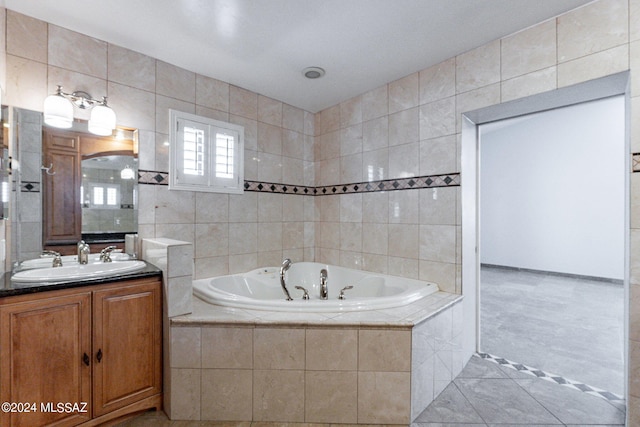 bathroom with tile walls, vanity, a relaxing tiled tub, and tile patterned floors