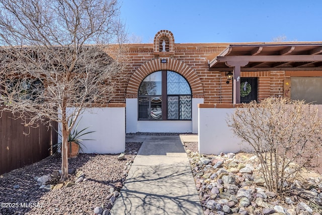 property entrance featuring brick siding and fence