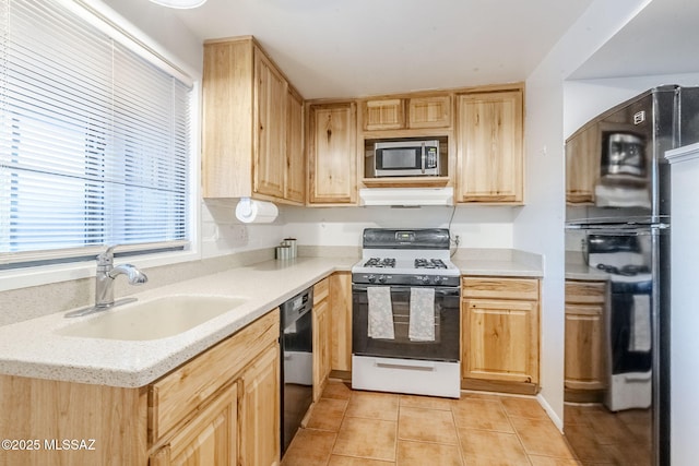 kitchen with light tile patterned floors, a sink, black appliances, and light brown cabinetry