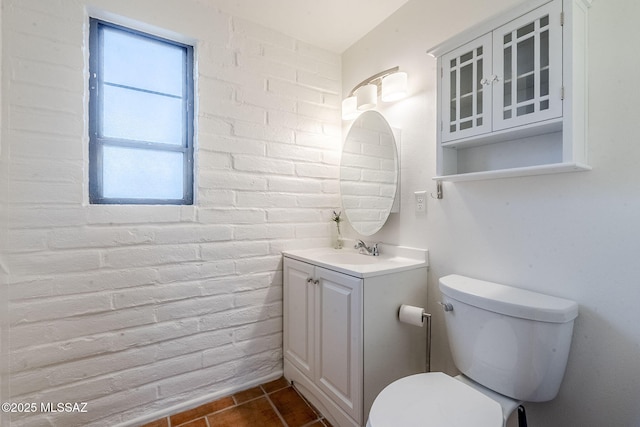 bathroom with brick wall, vanity, toilet, and tile patterned floors