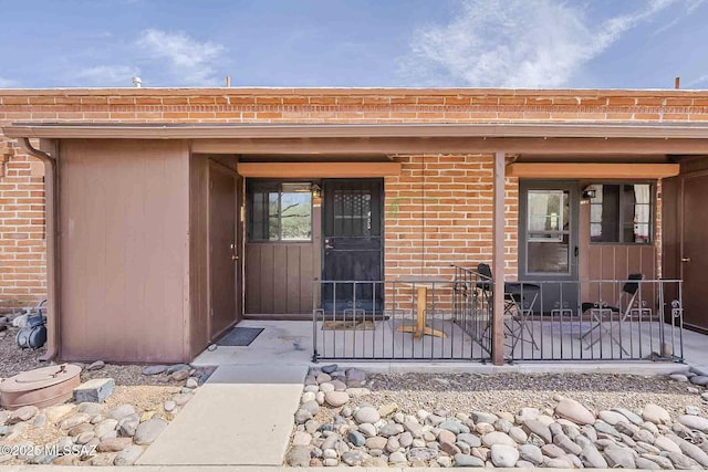 property entrance with covered porch and brick siding