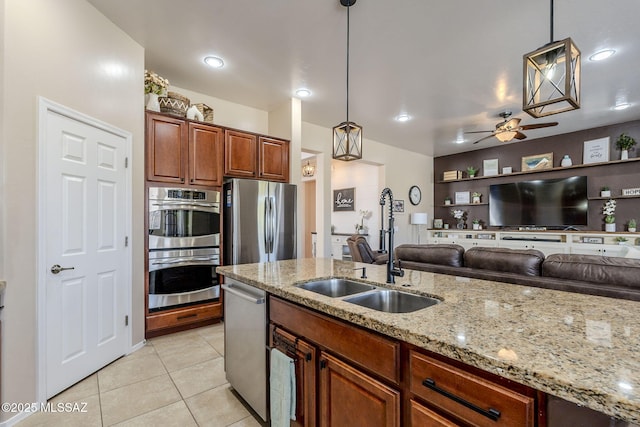 kitchen featuring light tile patterned floors, appliances with stainless steel finishes, pendant lighting, light stone counters, and sink