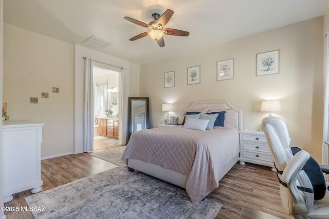 bedroom with light wood-type flooring, ceiling fan, and connected bathroom