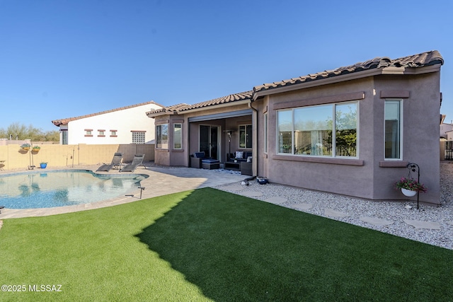 back of property featuring a patio area, a fenced in pool, and a lawn