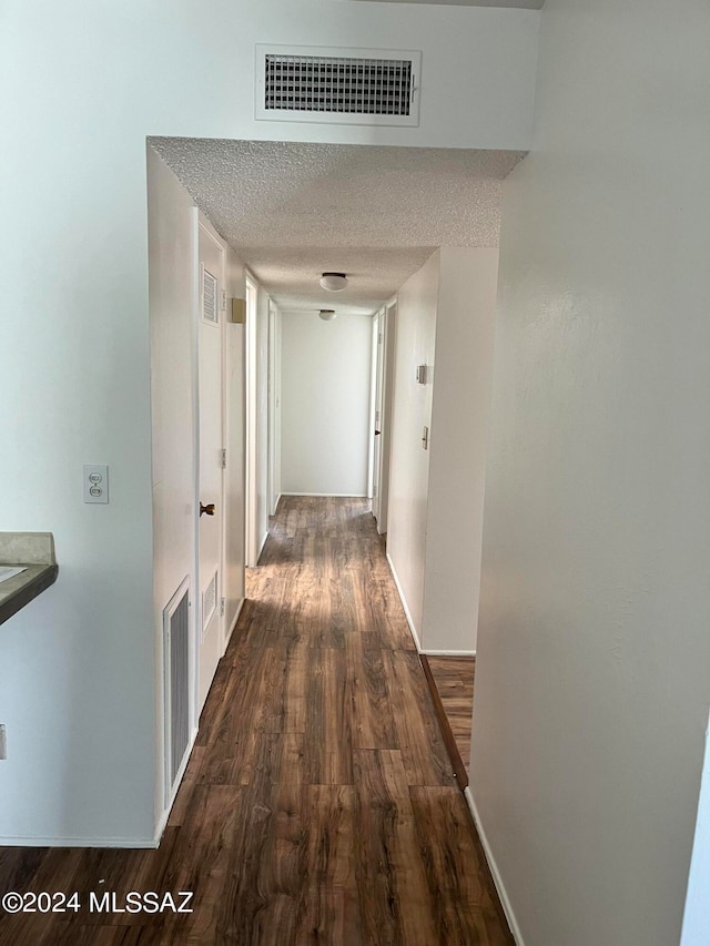 corridor featuring dark wood-type flooring and a textured ceiling