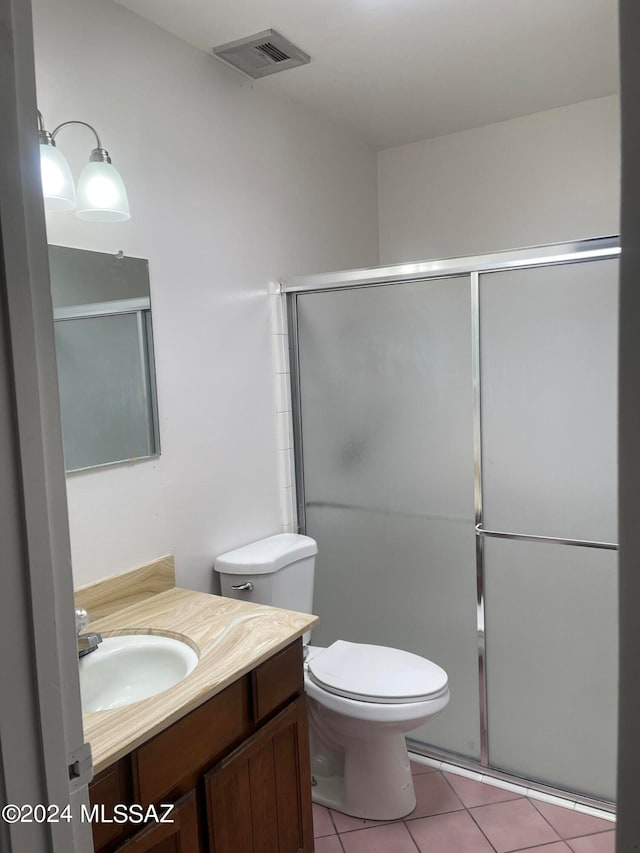 bathroom with vanity, a shower with shower door, toilet, and tile patterned floors