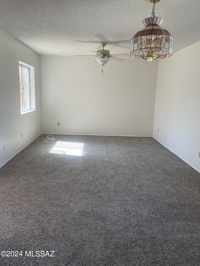 empty room featuring ceiling fan, a textured ceiling, and carpet floors