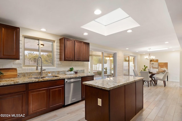 kitchen featuring sink, a skylight, light wood-type flooring, stainless steel dishwasher, and a kitchen island